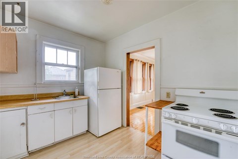 A kitchen with white appliances and wooden floors.