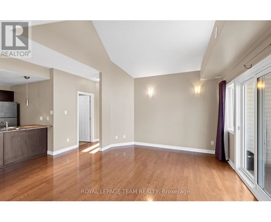 A spacious room with wooden floors and a kitchen area with a sink and stove.