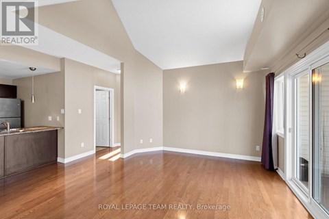 A spacious room with wooden floors and a kitchen area with a sink and stove.