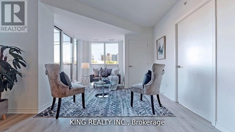 A living room with a couch, chairs, and a rug in front of a window.