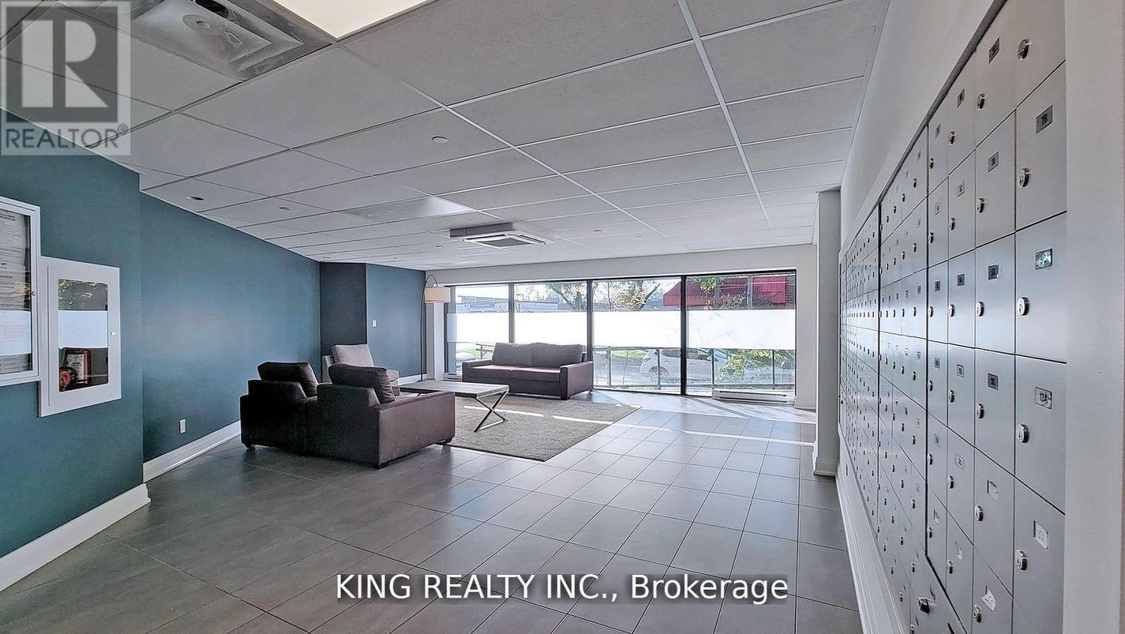 A spacious room with a row of lockers on the wall and a couch in the middle.