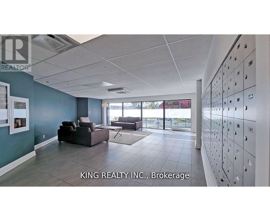 A spacious room with a row of lockers on the wall and a couch in the middle.