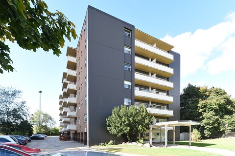 A grey and yellow building with a parking lot in front.