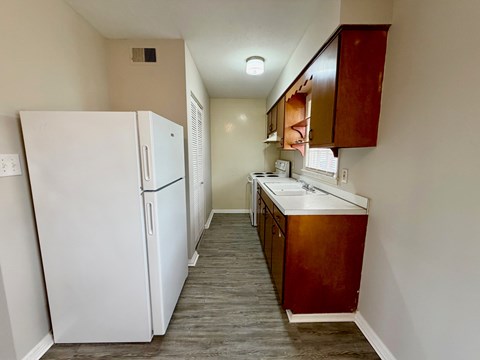 A kitchen with a white refrigerator and wooden cabinets.