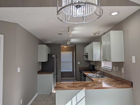 A kitchen with a wooden counter top and white cabinets.