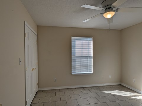 A room with a ceiling fan and a window with blinds.