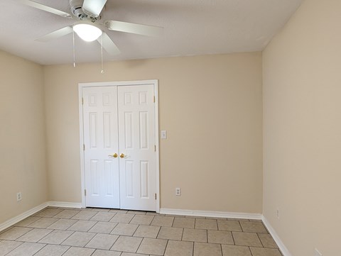 A room with a white door and a ceiling fan.
