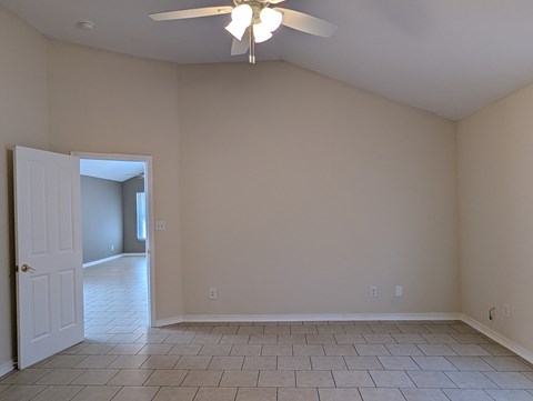 A room with a ceiling fan and tile flooring.