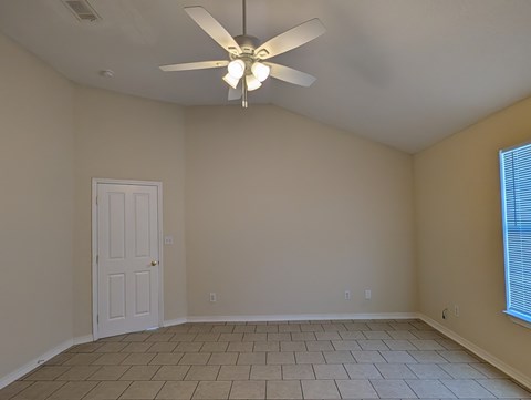 A room with a ceiling fan and tile flooring.