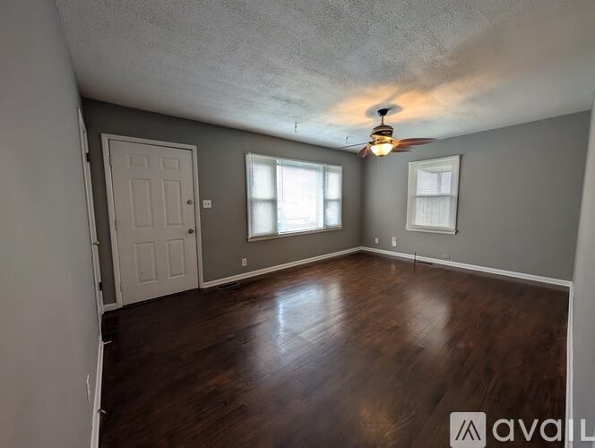 A room with a ceiling fan and wooden flooring.