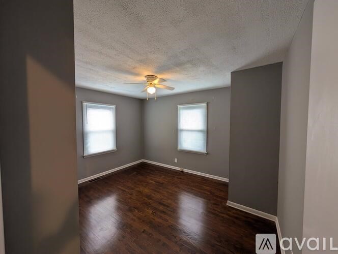 A room with wooden floors and two windows.