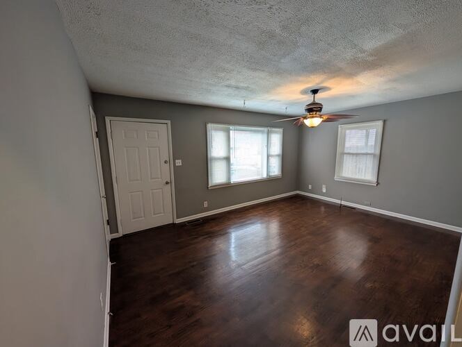 A room with a ceiling fan and wooden flooring.