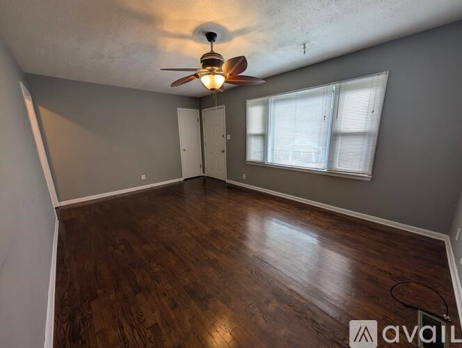 A room with a ceiling fan and wooden flooring.