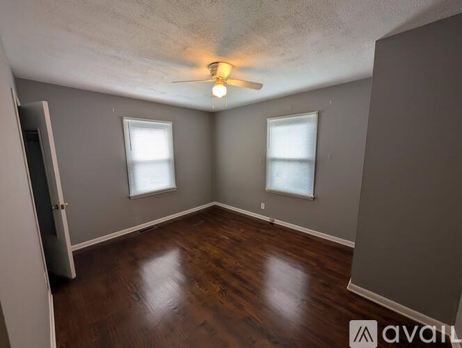 A room with wooden floors and two windows.