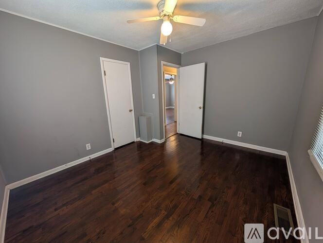 A room with a ceiling fan and wooden floors.