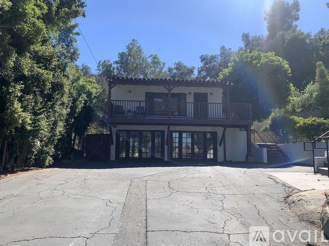 A house with a balcony is surrounded by trees.