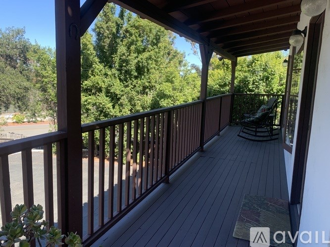 A wooden deck with a railing and a chair.