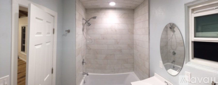 A white bathroom with a tub and a window.