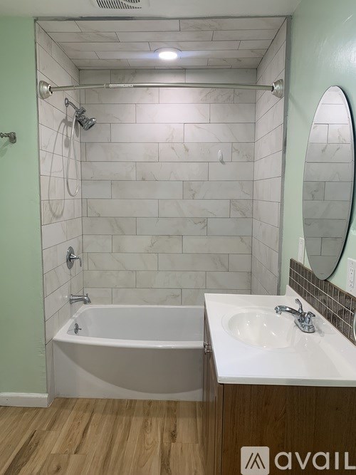 A bathroom with a tub, sink and mirror.