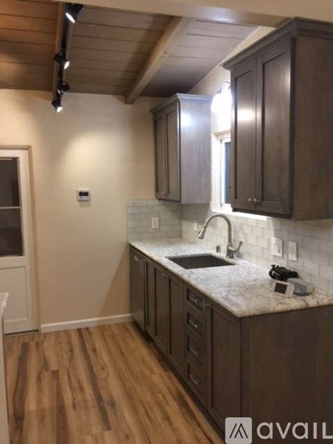 A kitchen with wooden cabinets and a marble countertop.