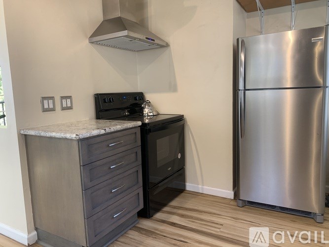A kitchen with a stainless steel refrigerator and a black oven.