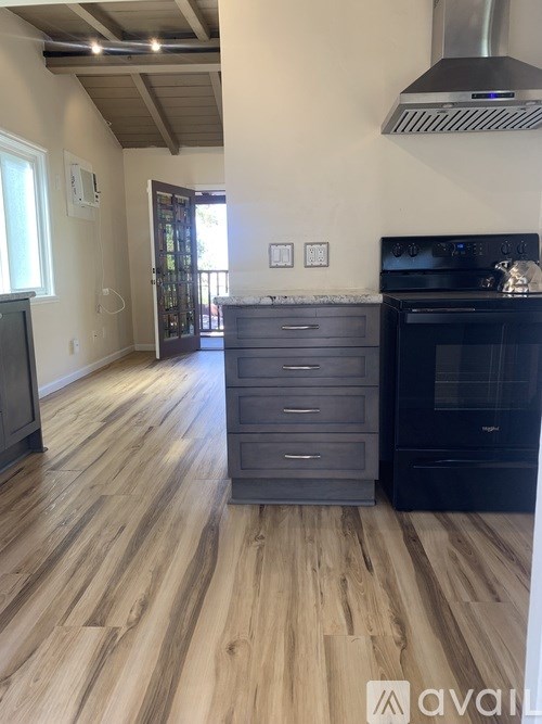 A kitchen with a black oven and wooden floors.