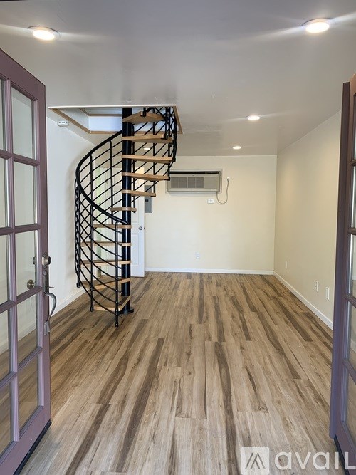 A spiral staircase in a room with wooden flooring and a white ceiling.
