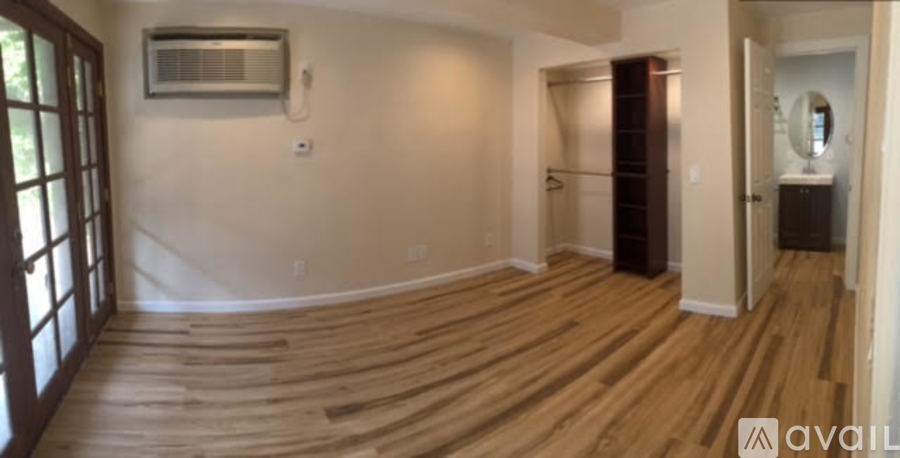 A room with wooden flooring and a window on the left side.