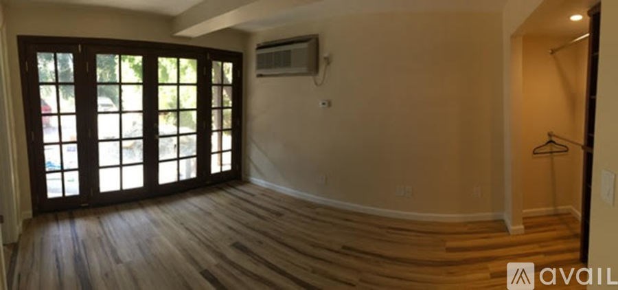 A room with wooden floors and a large window with a view of trees.