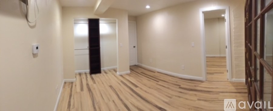 A hallway with wooden floors and a black column in the middle.