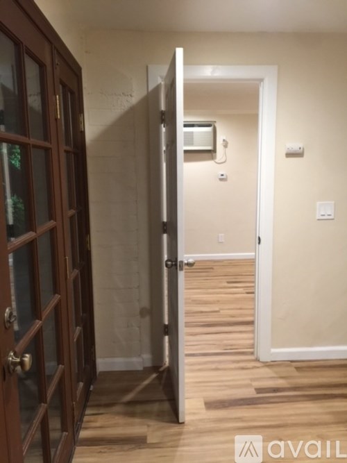 A hallway with a door on the left and a white door on the right.