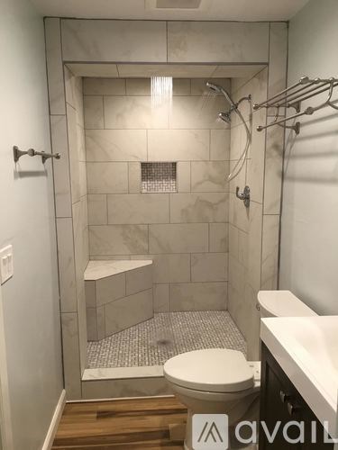 A white toilet is in a tiled shower stall.