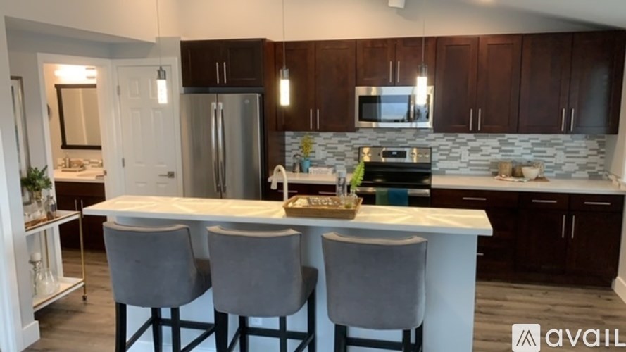 A kitchen with a white island and dark brown cabinets.