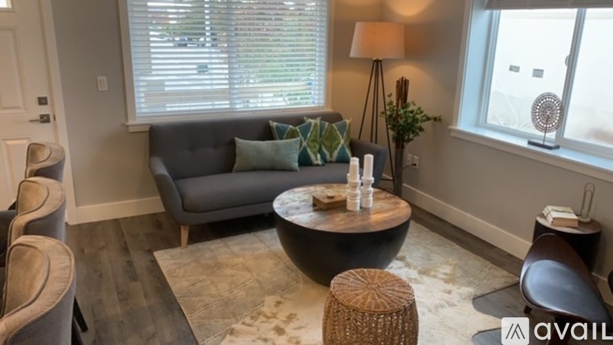 A living room with a grey couch, a round table, and a lamp.