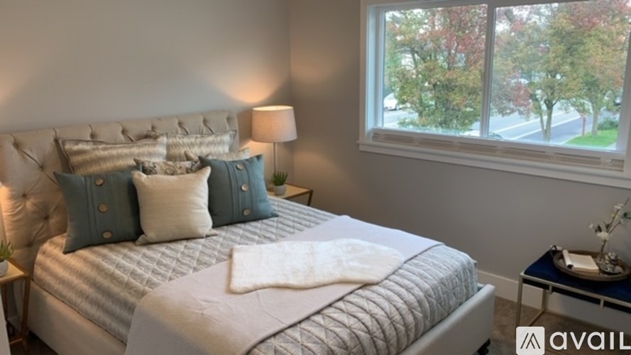 A bedroom with a large bed and a window overlooking a tree-lined street.