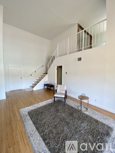 A living room with a white chair and a grey rug.