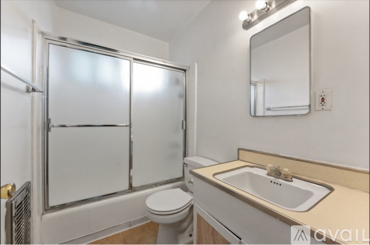 A bathroom with a toilet, sink, and mirror.