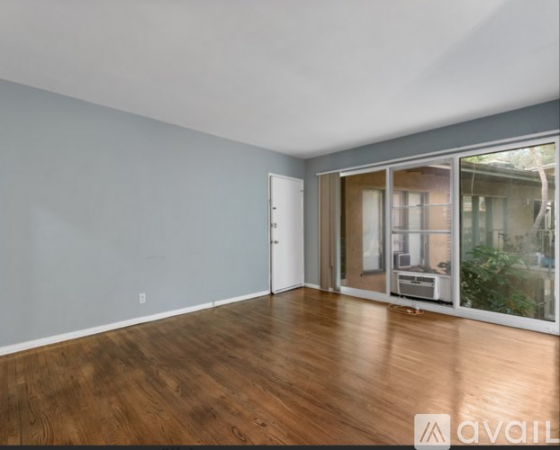 A room with wooden floors and a sliding glass door leading to a balcony.