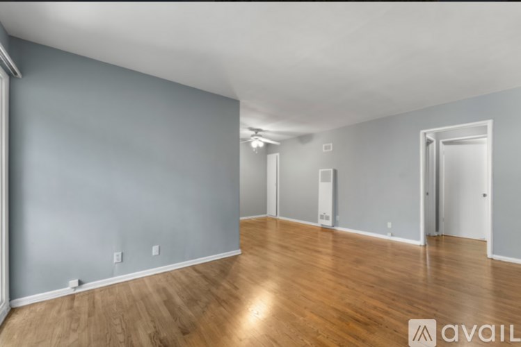 A spacious room with wooden floors and grey walls.