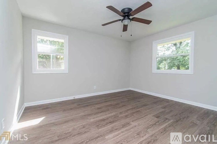A room with a ceiling fan and two windows.