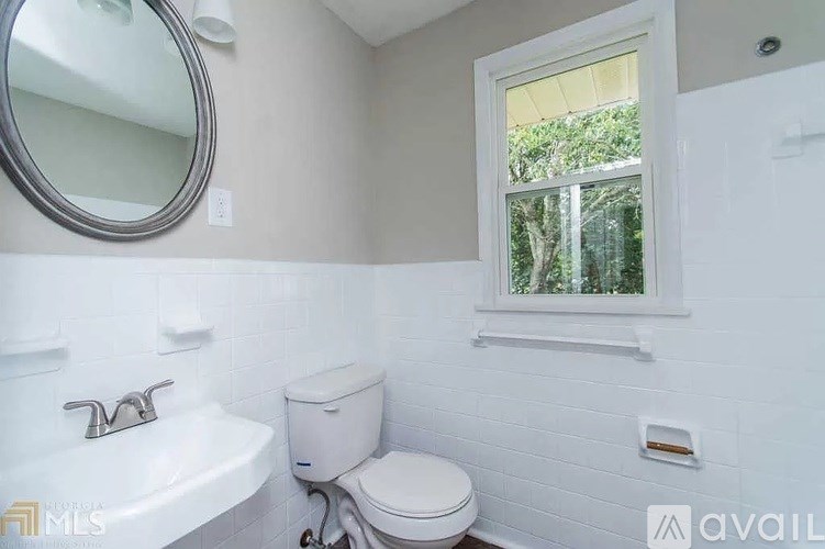 A white bathroom with a toilet, sink, and mirror.