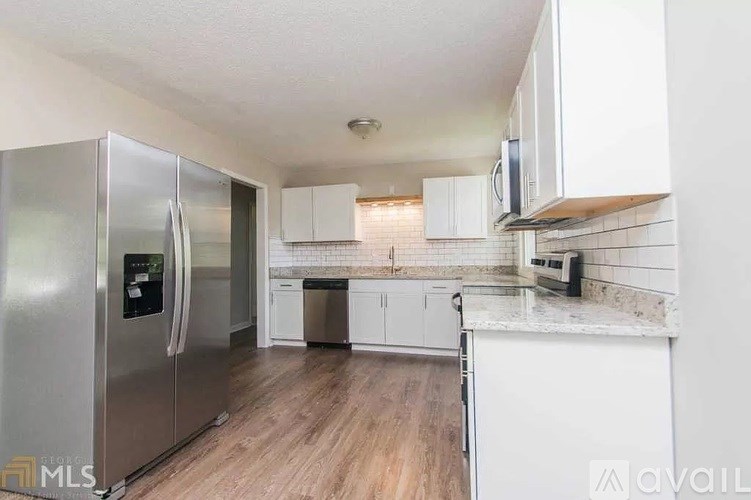 A kitchen with a stainless steel refrigerator and white cabinets.