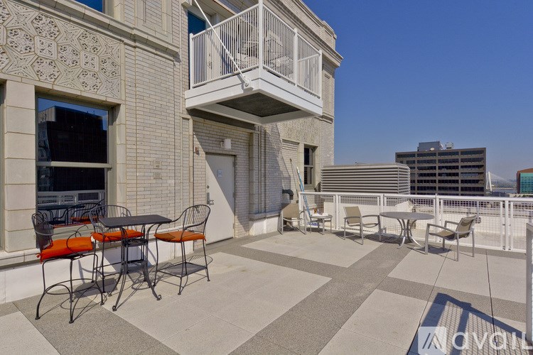 A balcony with a table and chairs overlooking a cityscape.