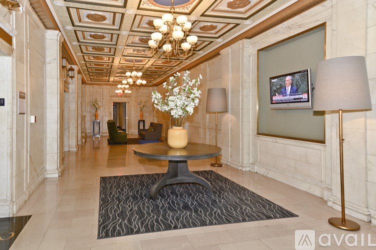 A large, elegant room with a chandelier, a table with a vase of flowers, and a television mounted on the wall.