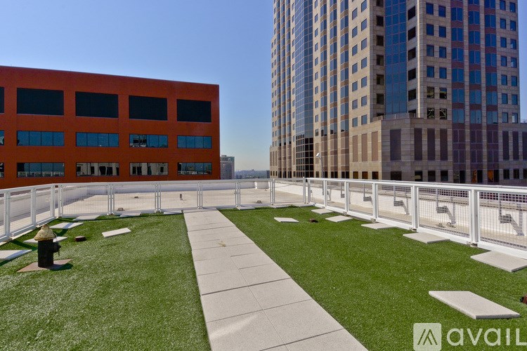 A rooftop patio with a white railing and a green lawn.