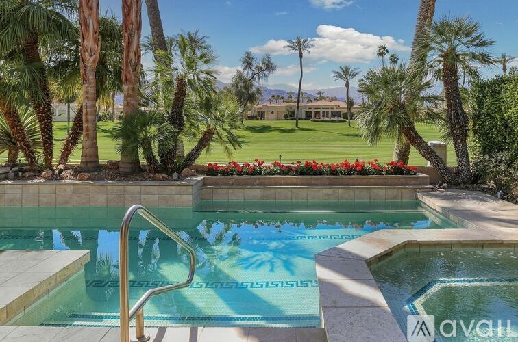 A pool surrounded by palm trees and red flowers.