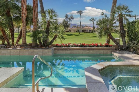 A pool surrounded by palm trees and red flowers.