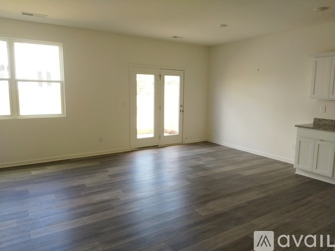 A room with wooden flooring and a large window.