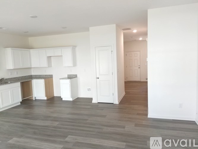 A spacious living room with a kitchen area in the background.