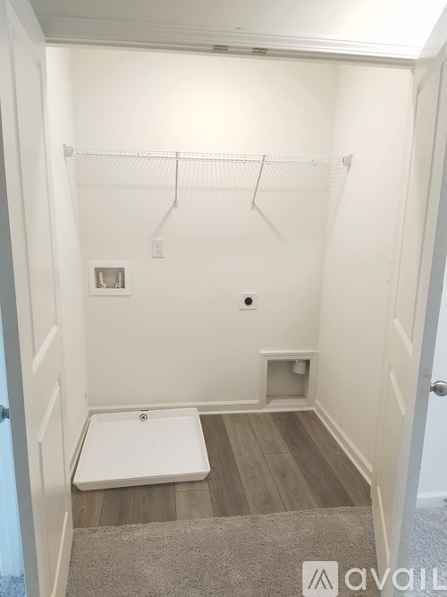 A small, white, walk-in closet with a door and a small white bench.
